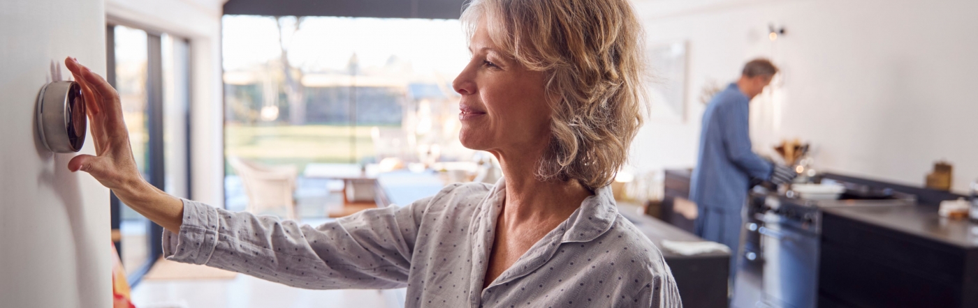 Woman adjusting thermostat